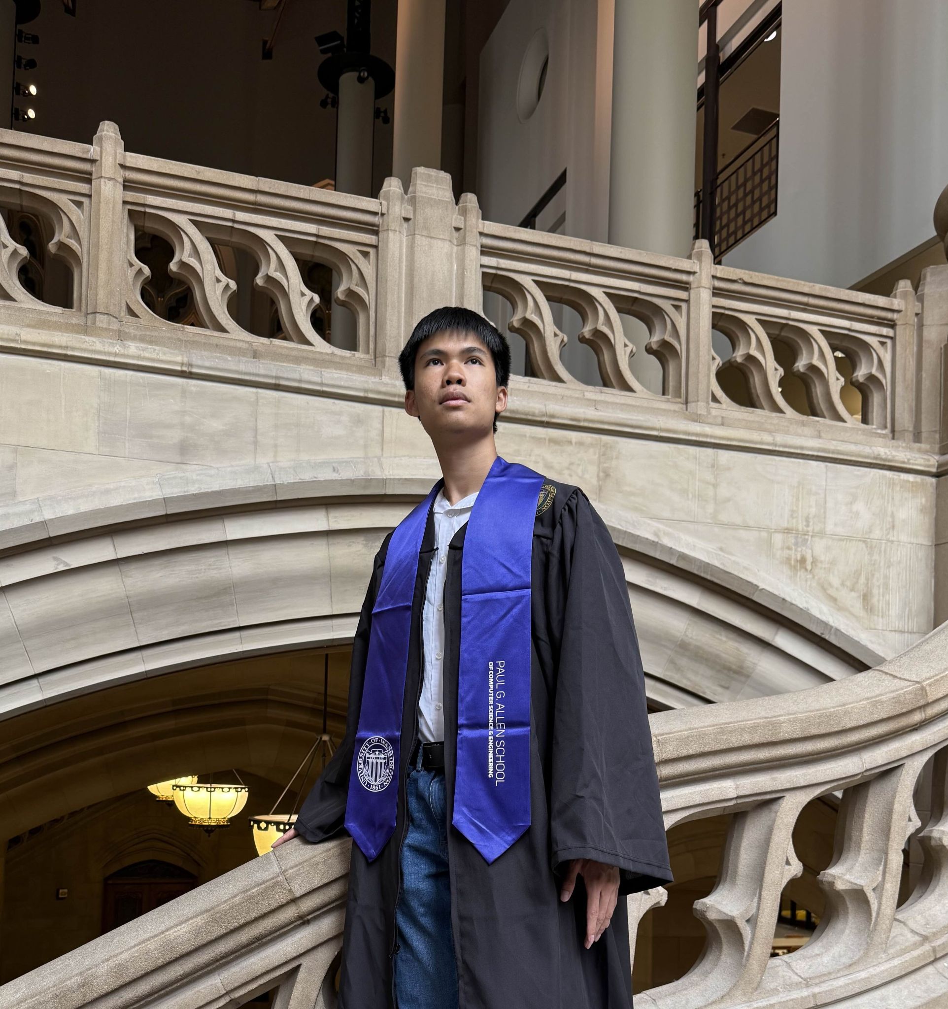 Michael Li in academic regalia beside a stone balustrade