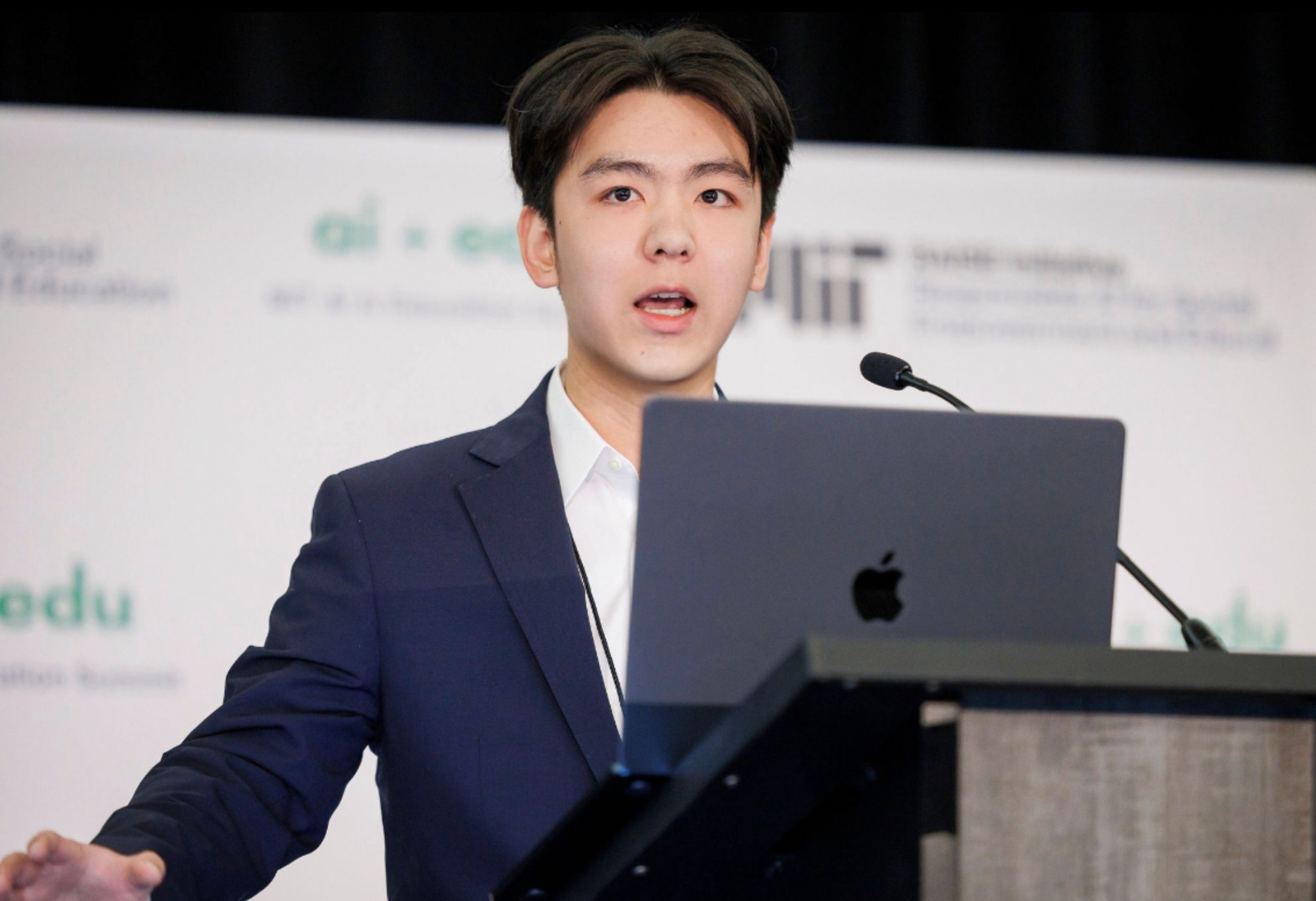 Tianyi Huang speaking at a lectern